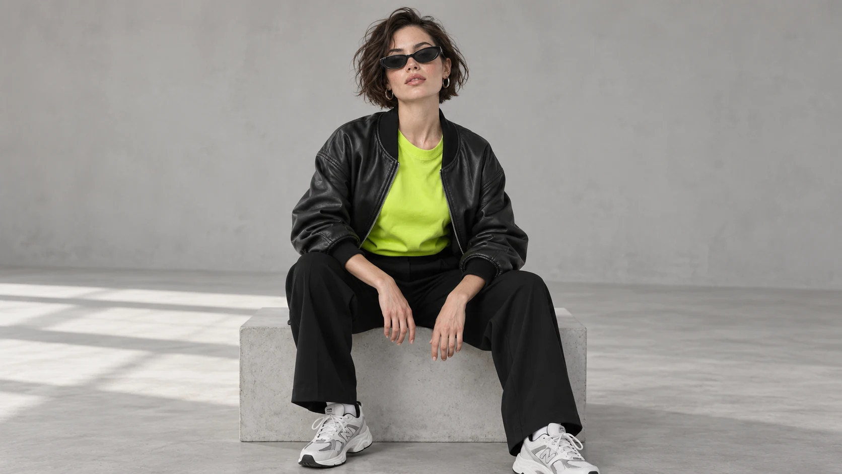 Modelka w czarnej kurtce bomber i limonkowej koszulce w studiu